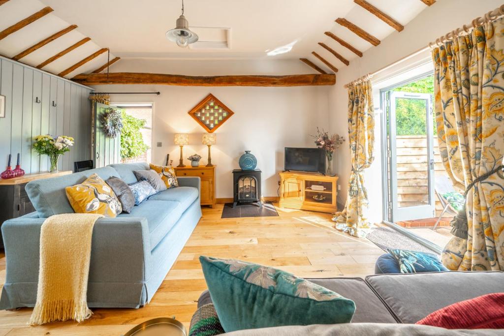 a living room with a blue couch and a fireplace at The Tack Room in Stowmarket