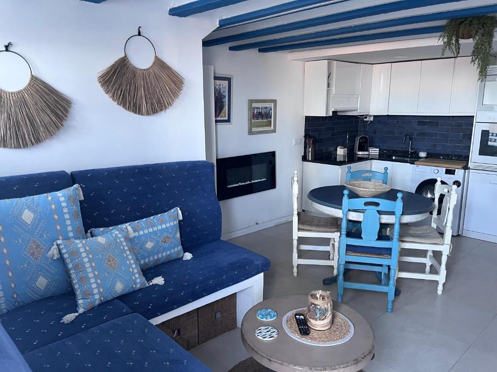 a living room with a blue couch and a kitchen at Casita pescadores recién reformada frente al mar in Torrenostra