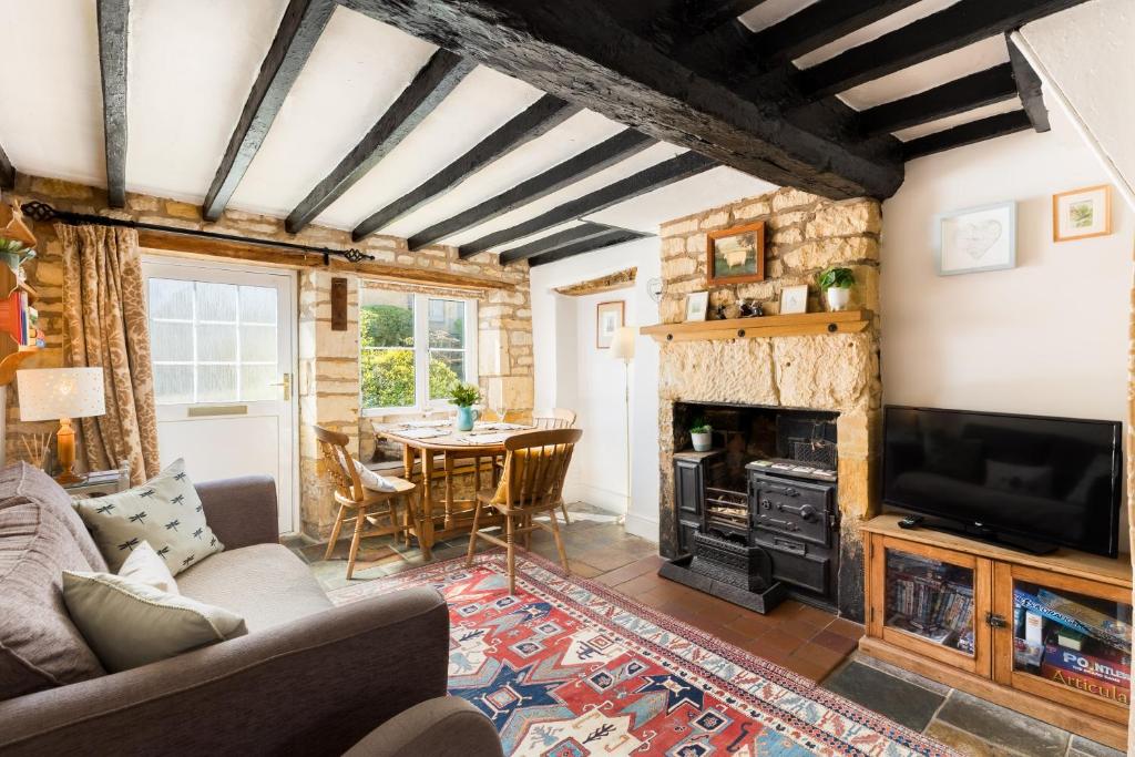 a living room with a fireplace and a table at Pass the Keys Cosy Cottage 17th century Garden Parking in Bourton on the Hill