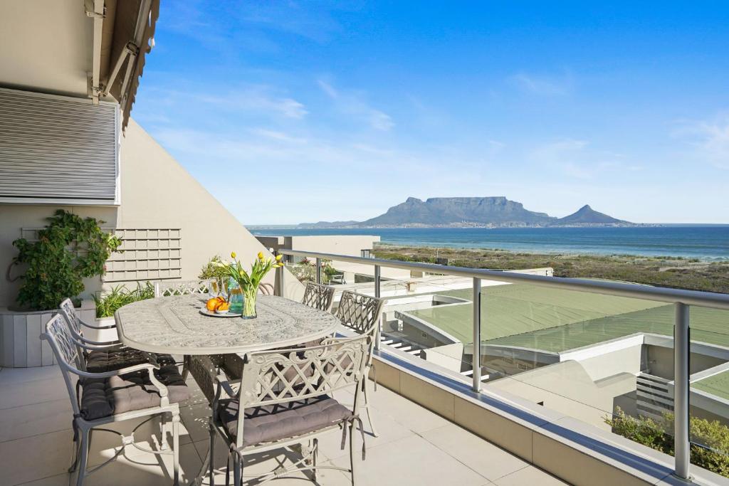 a balcony with a table and chairs and a view of the ocean at Dolphin Beach H106 by Host Agents in Bloubergstrand