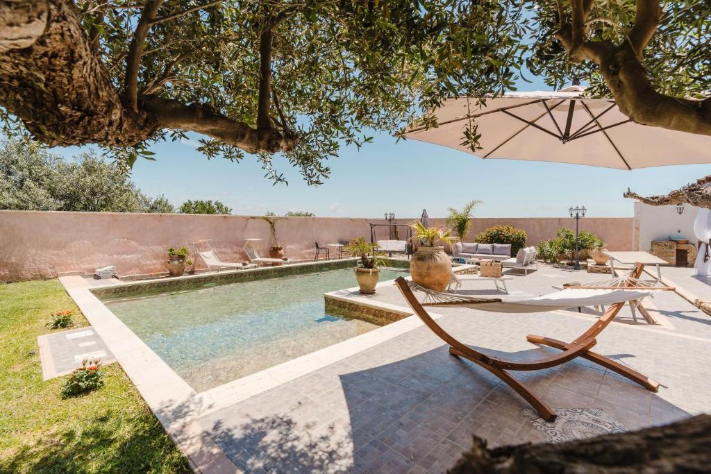 - une piscine avec des chaises et un parasol dans la cour dans l'établissement Le Giarre - Villa Con Piscina, à Marausa