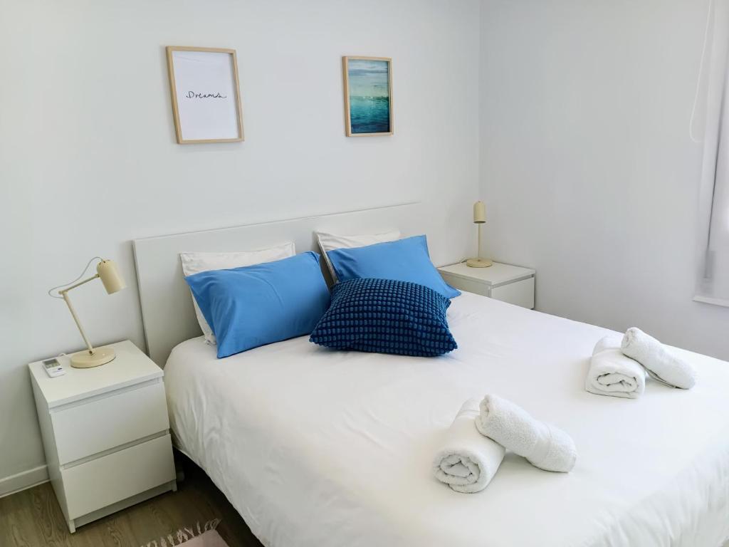 a white bed with blue pillows and towels on it at Lavrinha in Lavra