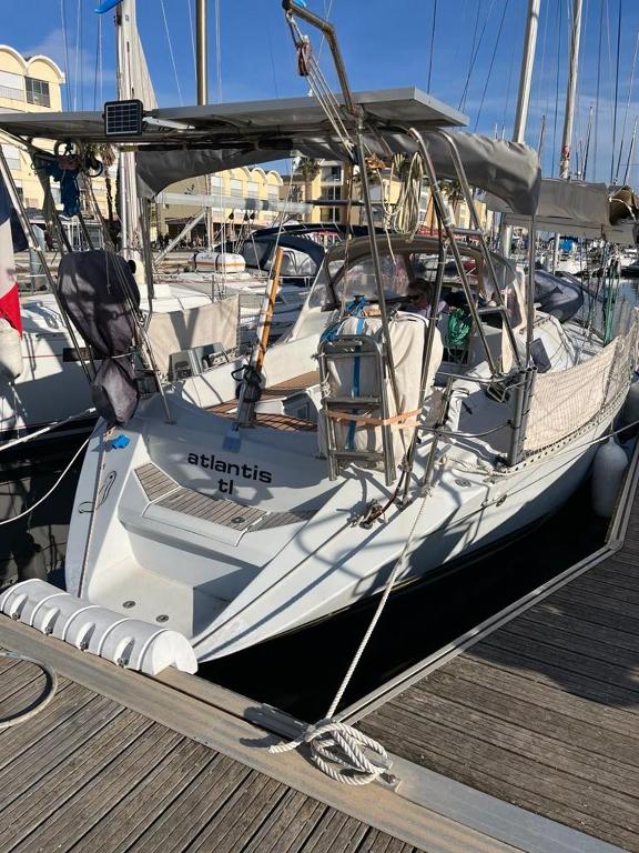 un bateau blanc amarré à un quai avec d'autres bateaux dans l'établissement Voilier atlantis, à Gruissan