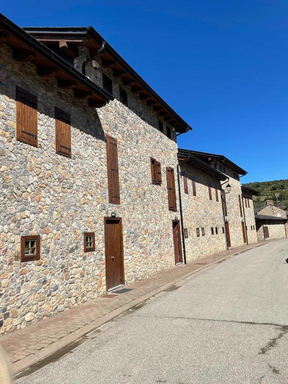 a stone building with wooden doors on the side of it at House surrounded by mountain and nature in Riu de Cerdanya
