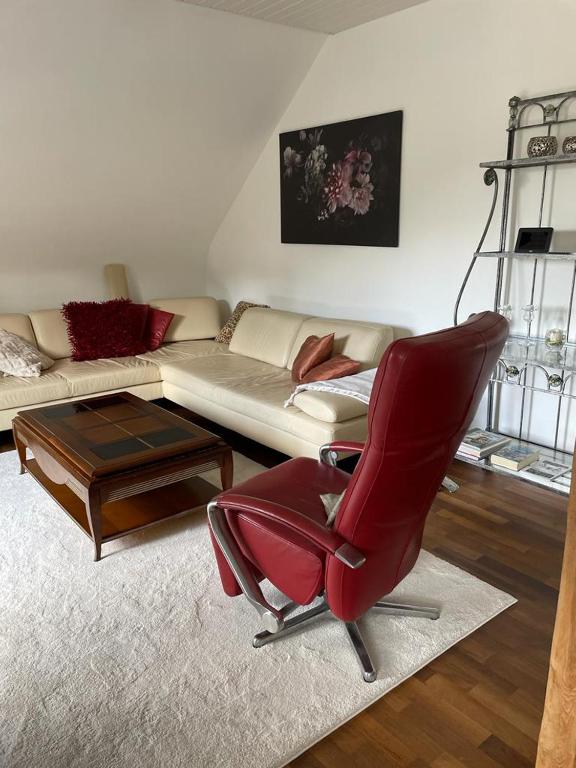 un salon avec une chaise rouge et un canapé dans l'établissement Ulrikesferienwohnung1, à Hombourg