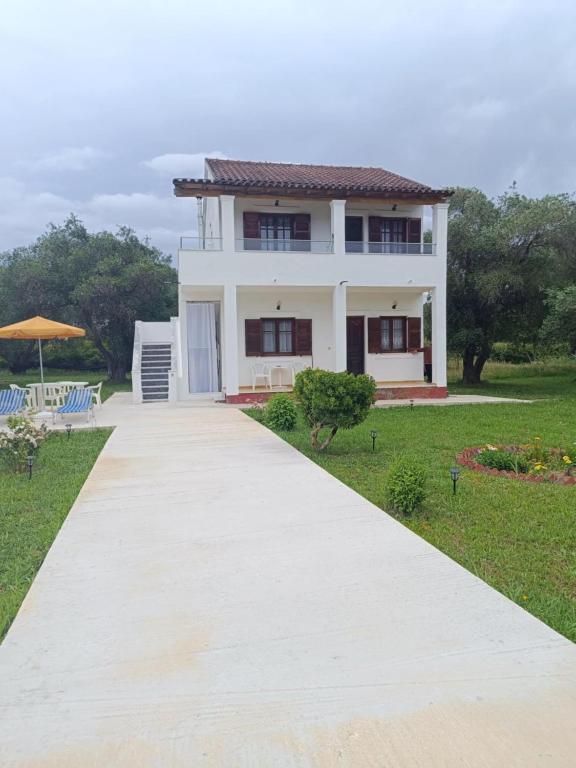 a white house with a pathway in front of it at Elvira Apartments in Roda