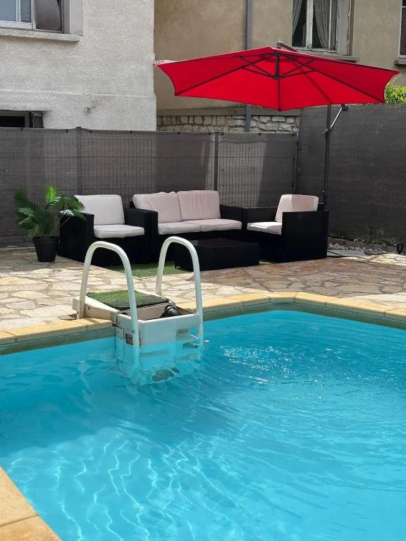 une piscine avec un parasol rouge à côté d'un canapé dans l'établissement Villa spacieuse avec piscine privée à Montpellier, à Montpellier