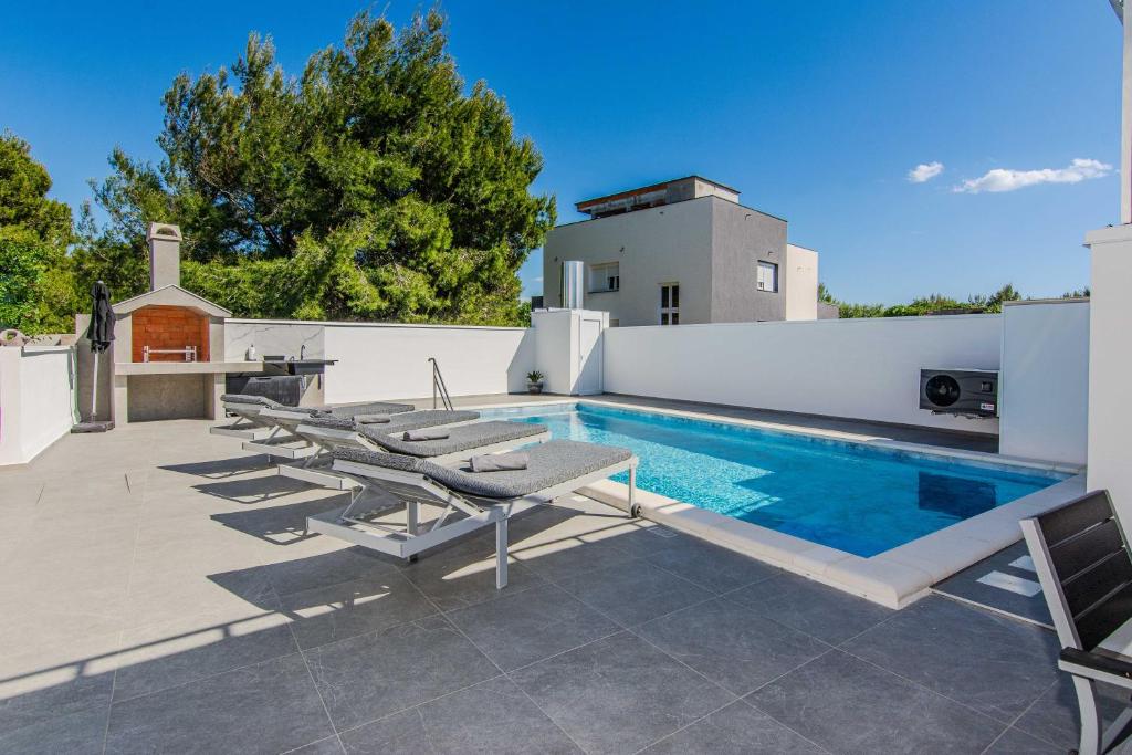 a swimming pool with chaise lounge chairs next to a house at Apartmani Sanja in Vir