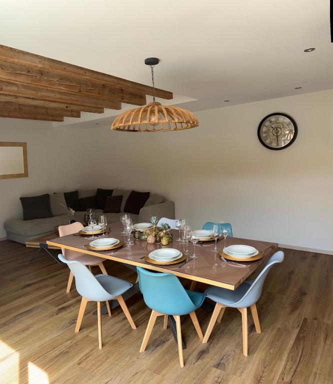 une table à manger avec des chaises bleues et une horloge dans l'établissement Gîte du Manala, à Wihr-au-Val