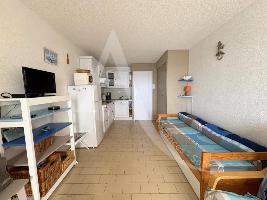 un salon avec un canapé et une cuisine dans l'établissement Studio cabine avec vue mer et parking, à Sète