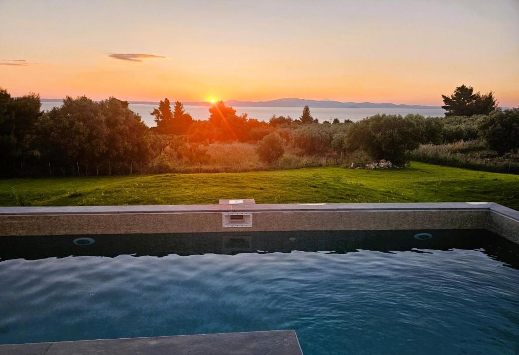 a swimming pool with the sunset in the background at Bellerive Villas in Kriopigi