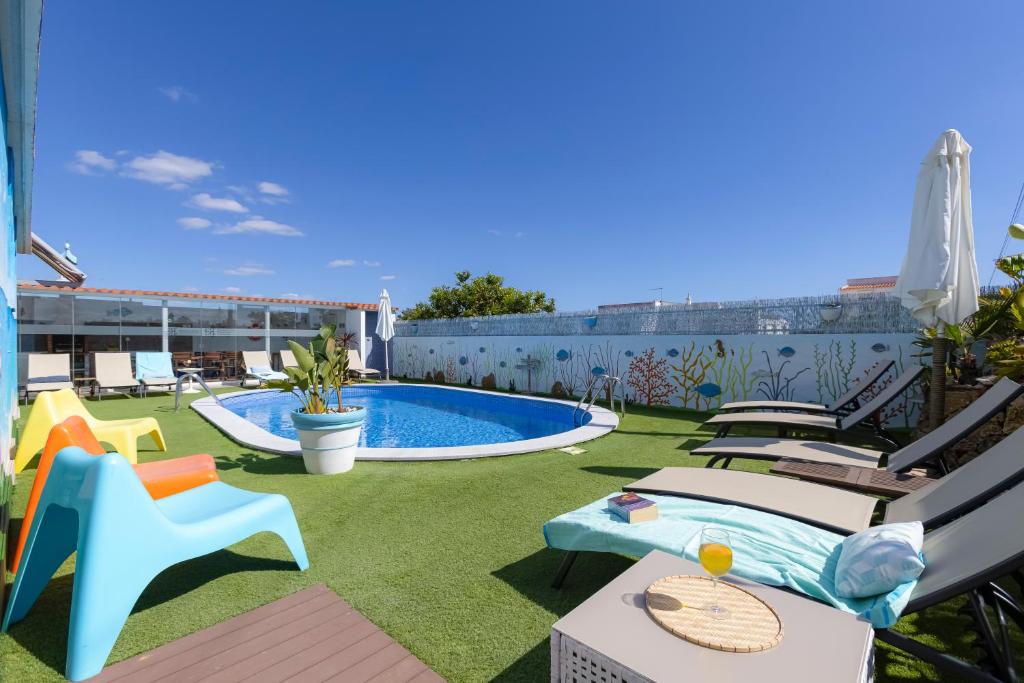 a backyard with a swimming pool and lawnitures at Bambus House Green in Quarteira