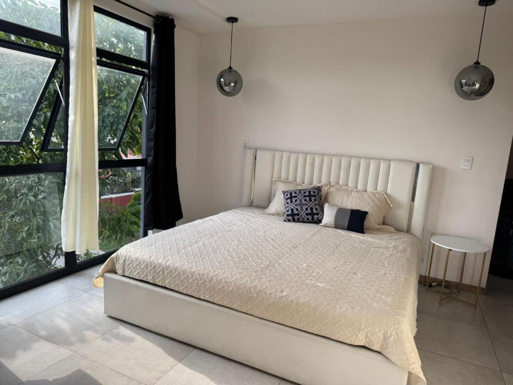 ein Schlafzimmer mit einem Bett und einem großen Fenster in der Unterkunft Dormitorio con baño privado es Tu descanso en el corazón de San Salvador in San Salvador