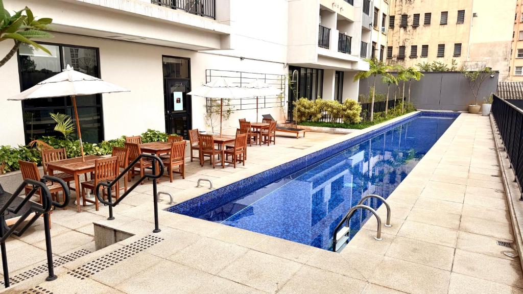 una piscina con tavoli e sedie accanto a un edificio di Apto Alto da Luz - 16º Andar a San Paolo