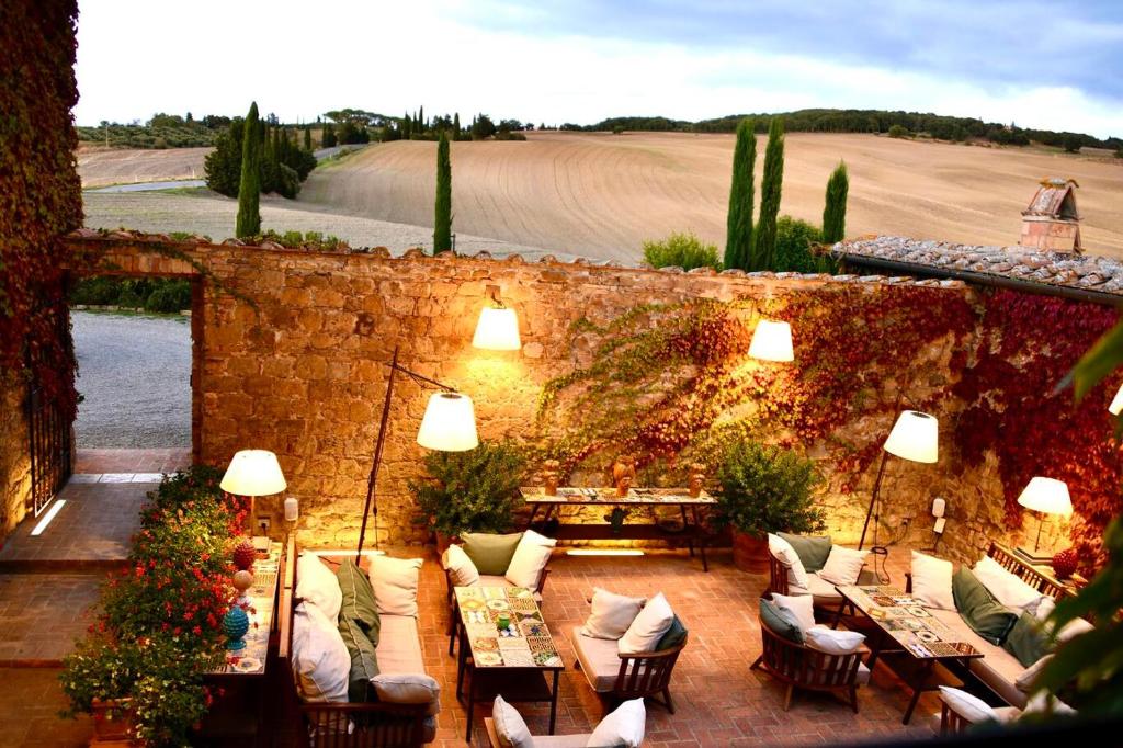 an outdoor patio with couches and tables and a field at L'Olmo in Monticchiello