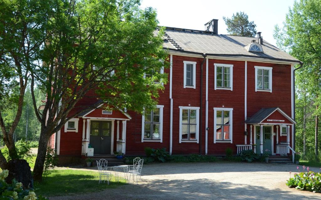 una casa roja con un árbol delante en Viljamaan kartano, en Kortteinen