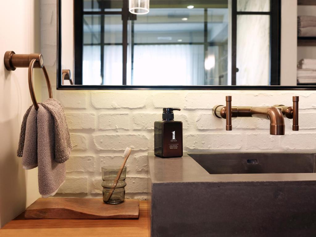a bathroom sink with a bottle of soap on a counter at 1 Hotel Central Park in New York
