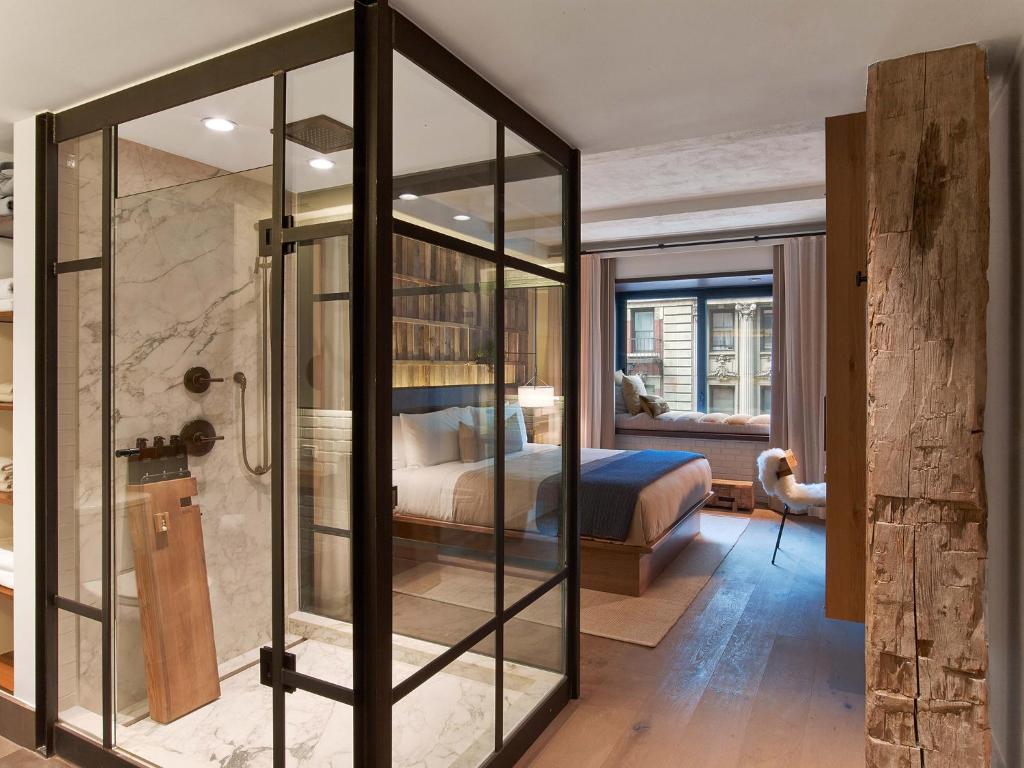 a master bedroom with a bed and a glass shower at 1 Hotel Central Park in New York