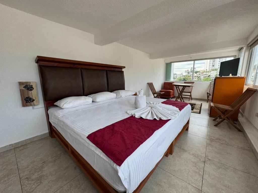 a bedroom with a large bed with a red and white blanket at VILLA COSTERA HOTEL BOUTIQUE in Acapulco