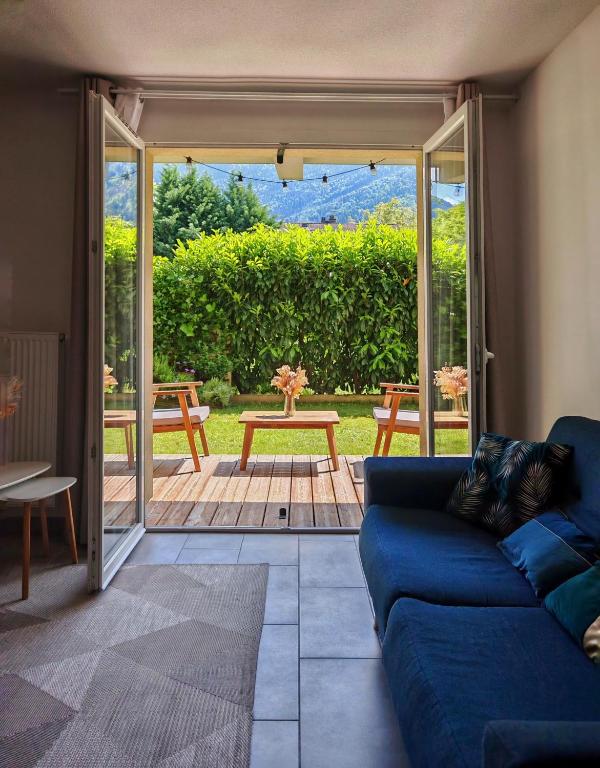 un salon avec un canapé bleu et une terrasse dans l'établissement Appartement avec jardin, à Saint-Gervais-les-Bains