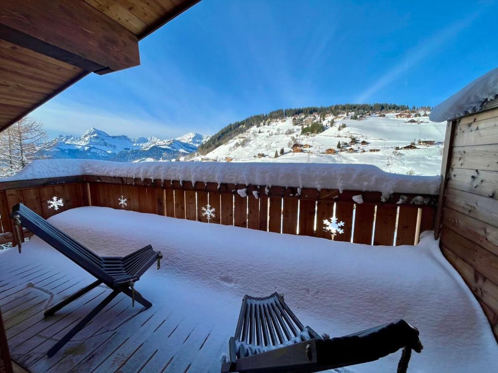une terrasse enneigée avec un banc et des montagnes enneigées dans l'établissement Duplex neuf au pied des pistes avec WiFi et parking privé - FR-1-505-203, à Notre-Dame-de-Bellecombe