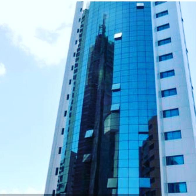 a tall glass building with a reflection of a skyscraper at Betel Flat Executive Praia Boa Viagem in Recife