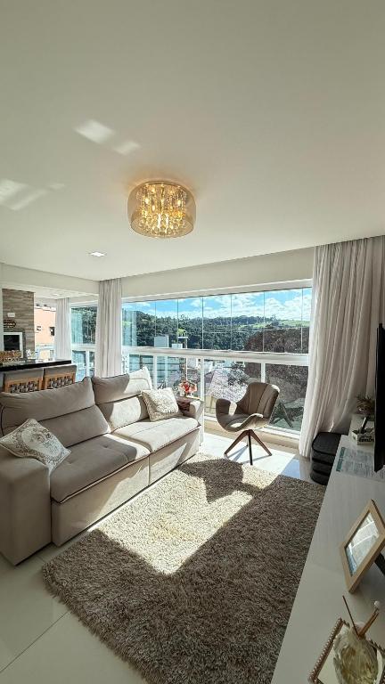 a living room with a couch and a large window at Apto Das Margaridas- 3 Quartos, Apto todo climatizado, amplo, confortável, ao lado do Parque Termal!! in Piratuba