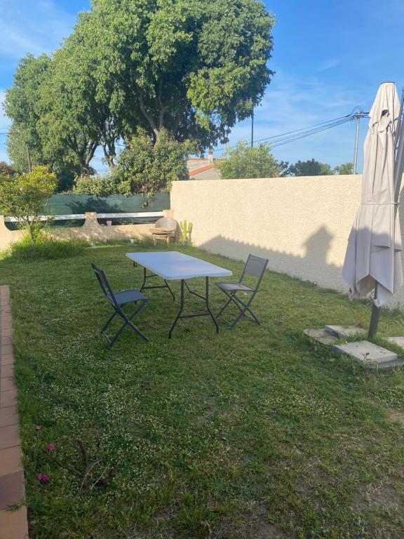 a table and chairs in a yard with an umbrella at Maison 4 personnes Sorède in Sorède