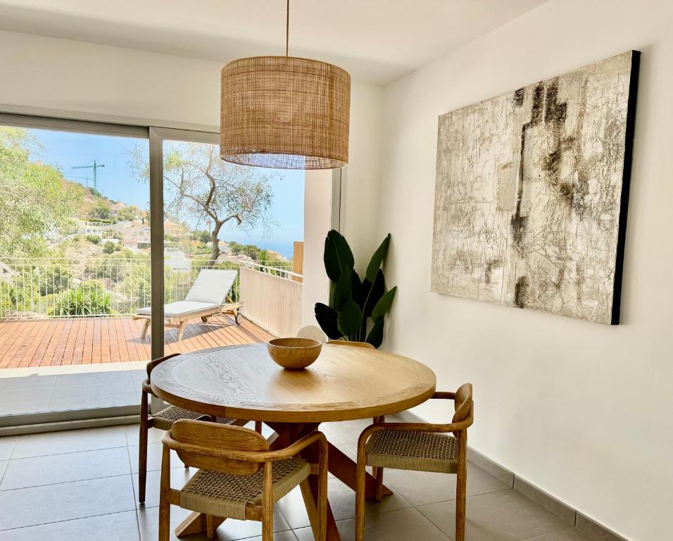 a dining room with a wooden table and chairs at Althaia Hills - Precioso adosado con terraza panorámica al mar y montaña in Altea