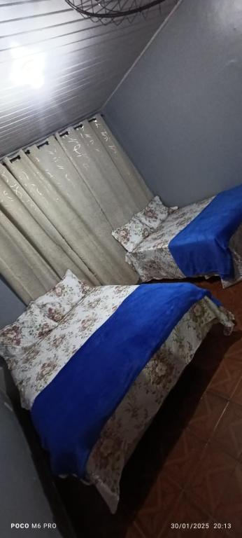 a bed with blue sheets and pillows next to a window at Pousada Pôr do sol in Belém