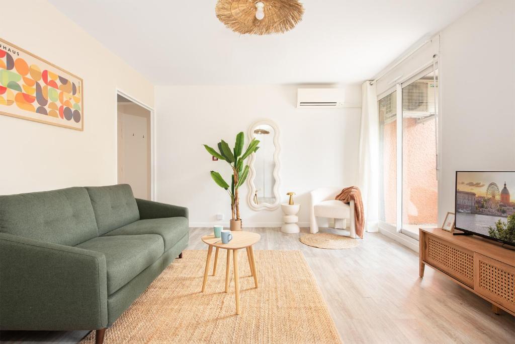 a living room with a green couch and a tv at T2 Aéroport Blagnac Toulouse - 1 à 4p - CLIM - Parking in Blagnac