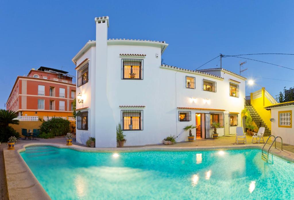 a villa with a swimming pool in front of a house at Precioso chalet con gran algarrobo y piscina privada in La Jara