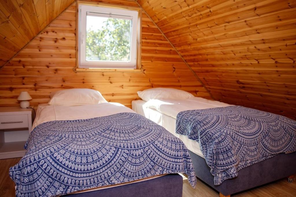 two beds in a log cabin with a window at Domki u Rybaka in Kąty Rybackie