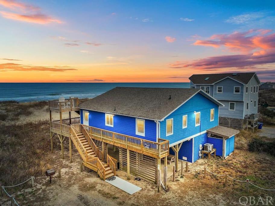 een blauw huis op het strand bij zonsondergang bij Oceanfront Views Private Beach Access and Hot Tub in Nags Head