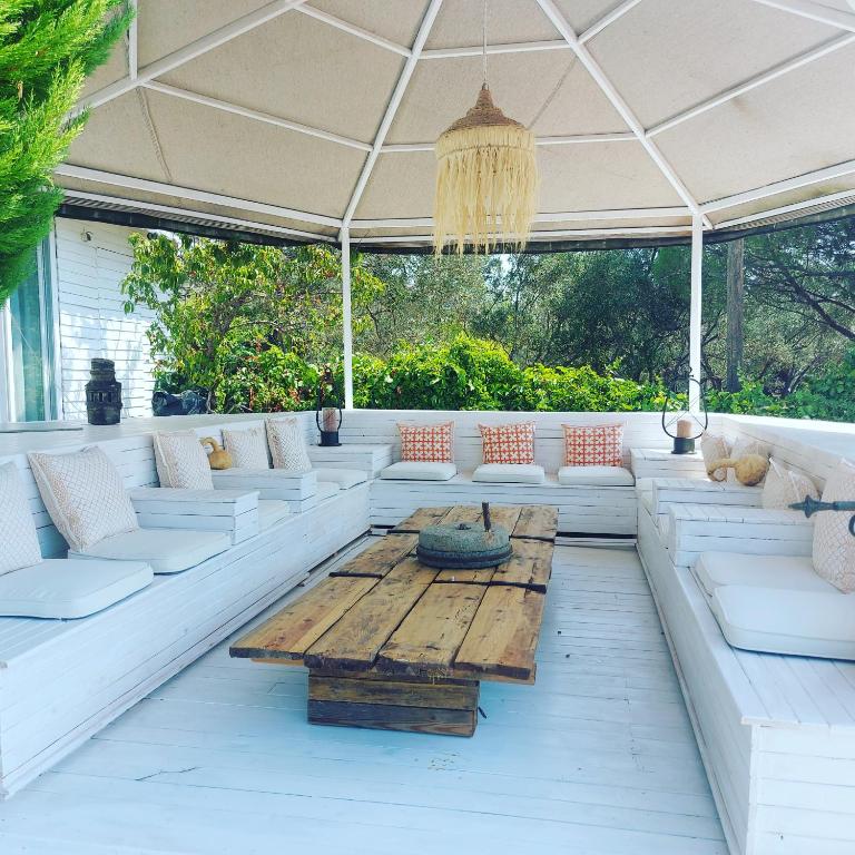 a porch with white couches and a wooden table at Sazlı Shores in Ayvacık