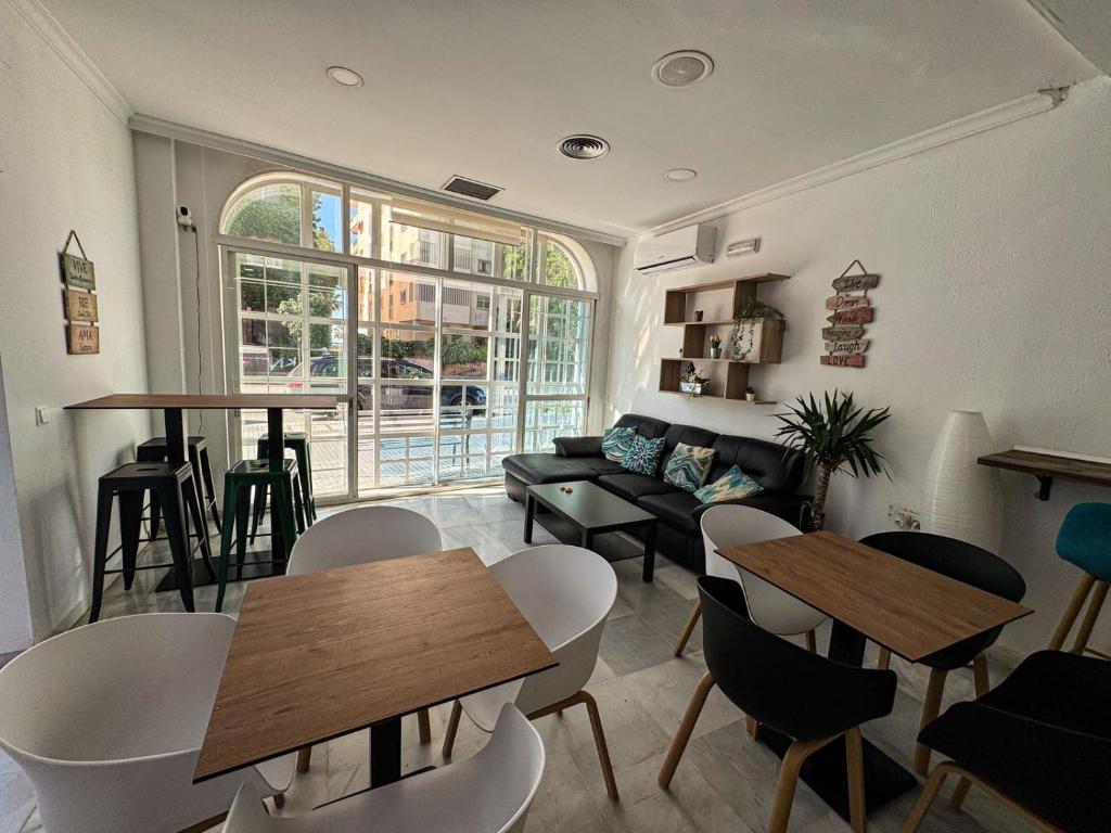 a living room with tables and chairs and a couch at Hostel Sorolla Playa in Málaga