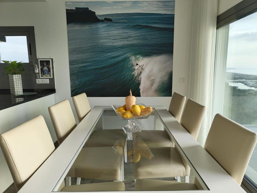 een eetkamer met een glazen tafel en stoelen bij Maçarico's Guest House in Nazaré
