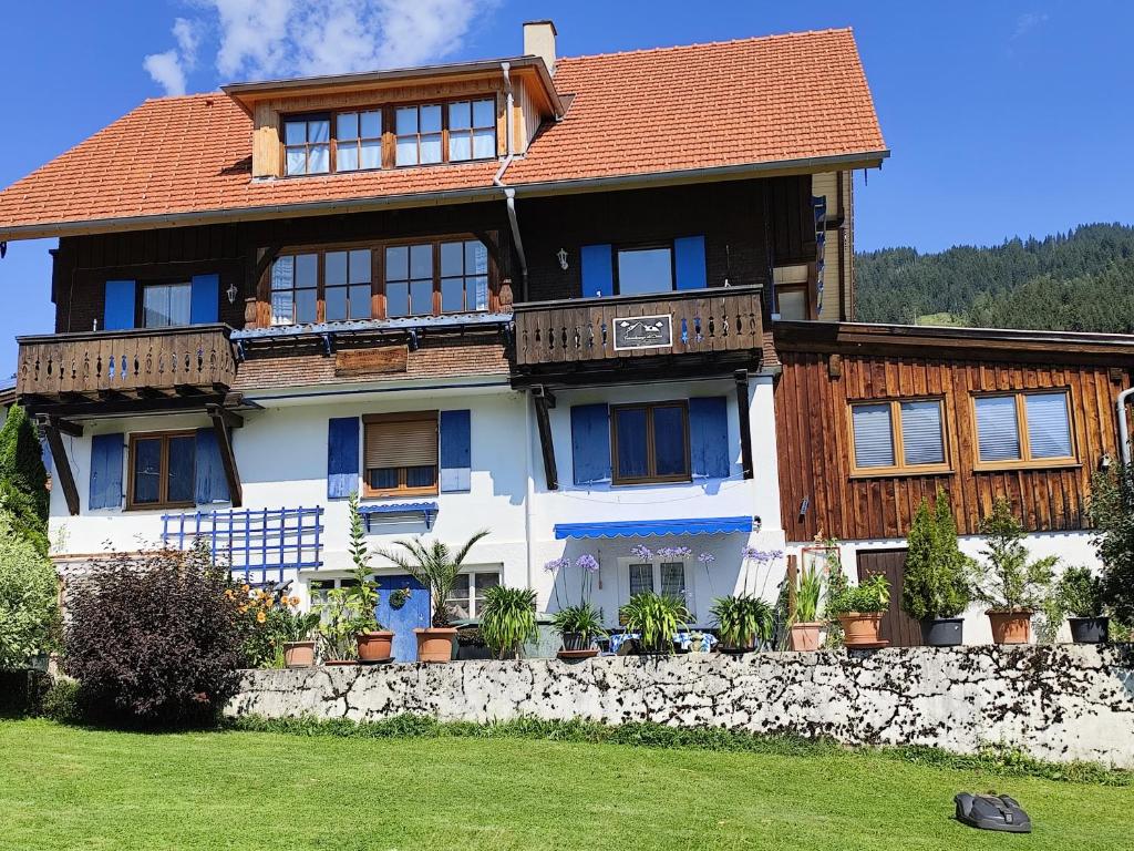 a large wooden house with a stone wall at Haus Daheim in Bad Hindelang
