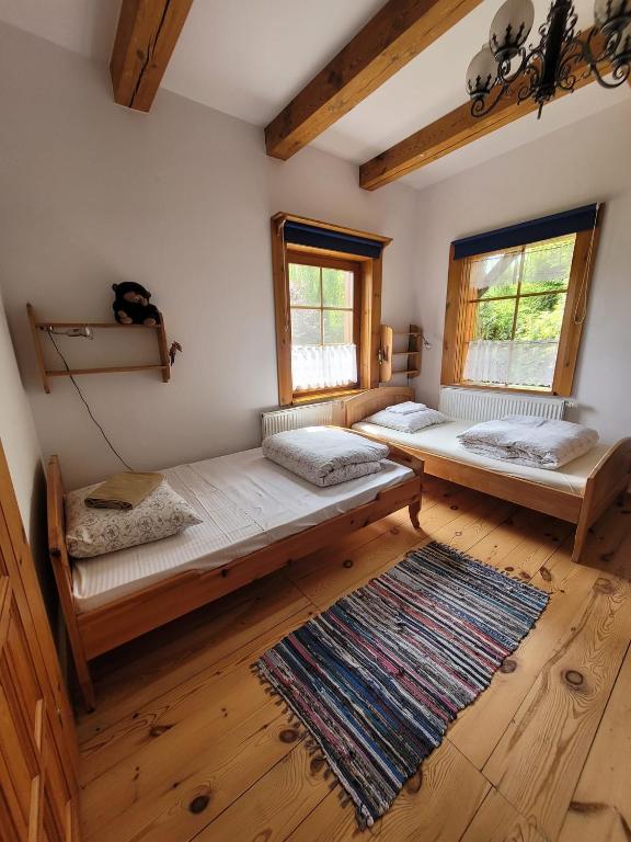 two beds in a room with wooden floors and windows at Pokoje Gościnne Wojtek-2 in Białowieża