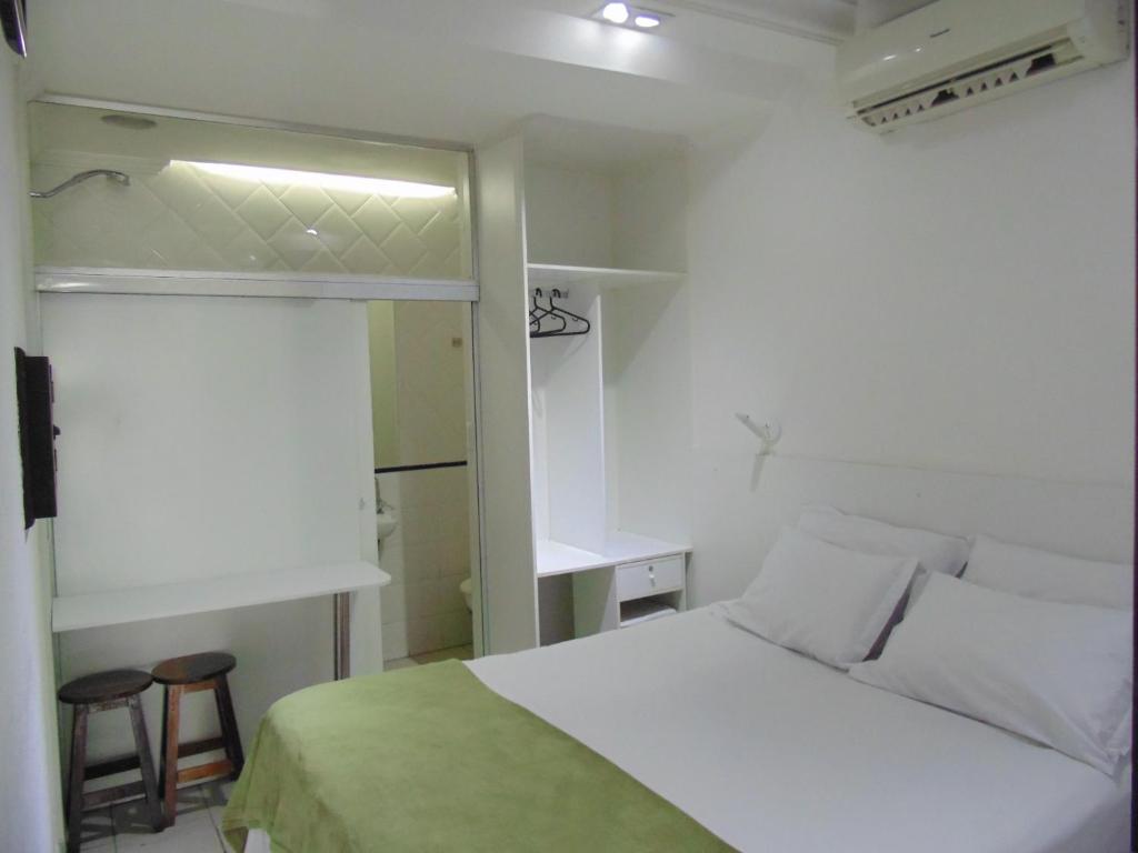 a bedroom with a white bed with a green blanket at Amarhotel in Sao Paulo