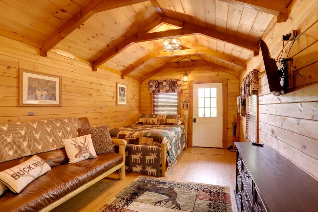 Dormitorio en cabaña de madera con sofá y cama en 1 Mi to Current River Cozy Studio Cabin!, en Van Buren