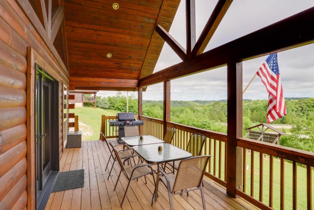 un porche cubierto con mesa, sillas y bandera americana en Family Cabin with Deck By Mark Twain Natl Forest!, en Van Buren
