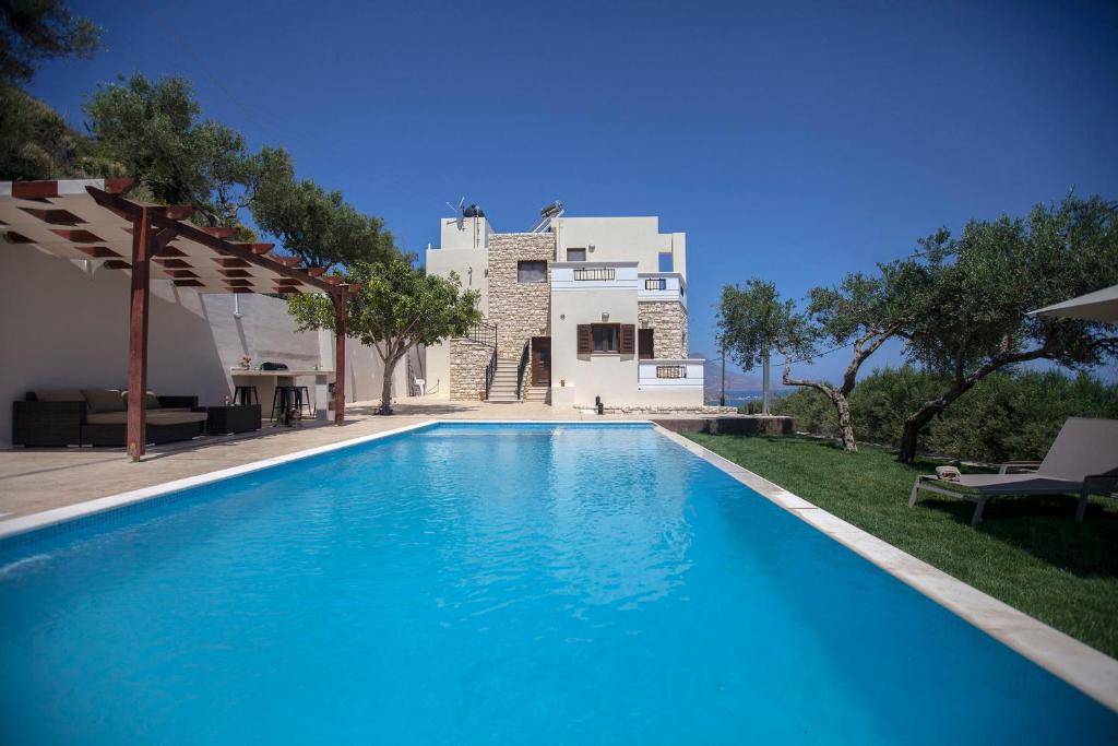 una piscina azul frente a una casa en Villa Veghera, en Kissamos