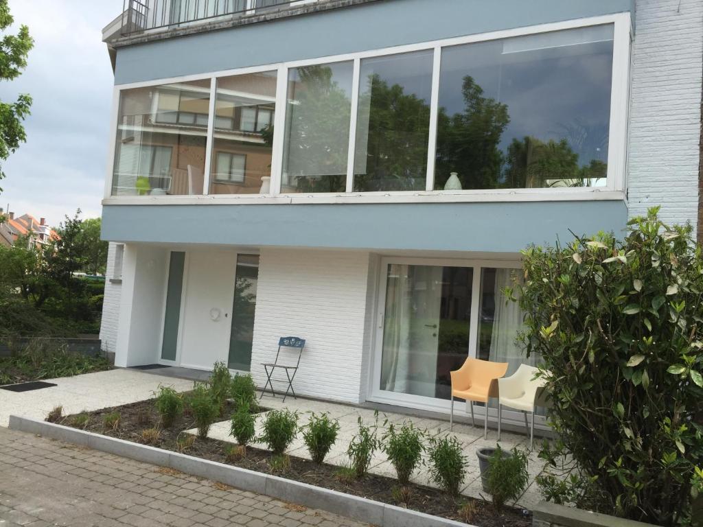ein Haus mit Fenstern und zwei Stühlen davor in der Unterkunft Guesthouse Poppies in Ostende