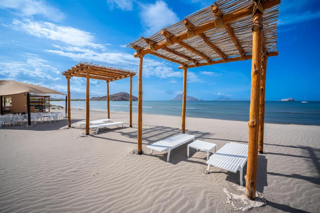 a group of benches on a beach with the ocean at Stylish Summer 2BR Retreat w Pool & Beach Access in Ensenada Blanca