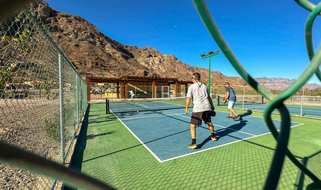 Dos personas jugando al tenis en una cancha de tenis en Danzante Bay Oceanfront 2 BR Beach & Golf, en Ensenada Blanca