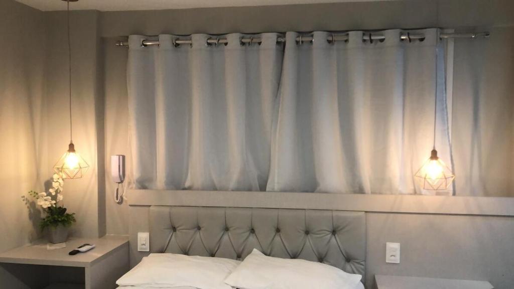 a bedroom with a bed and a window with white curtains at Paradise Beach Flat 211 in João Pessoa