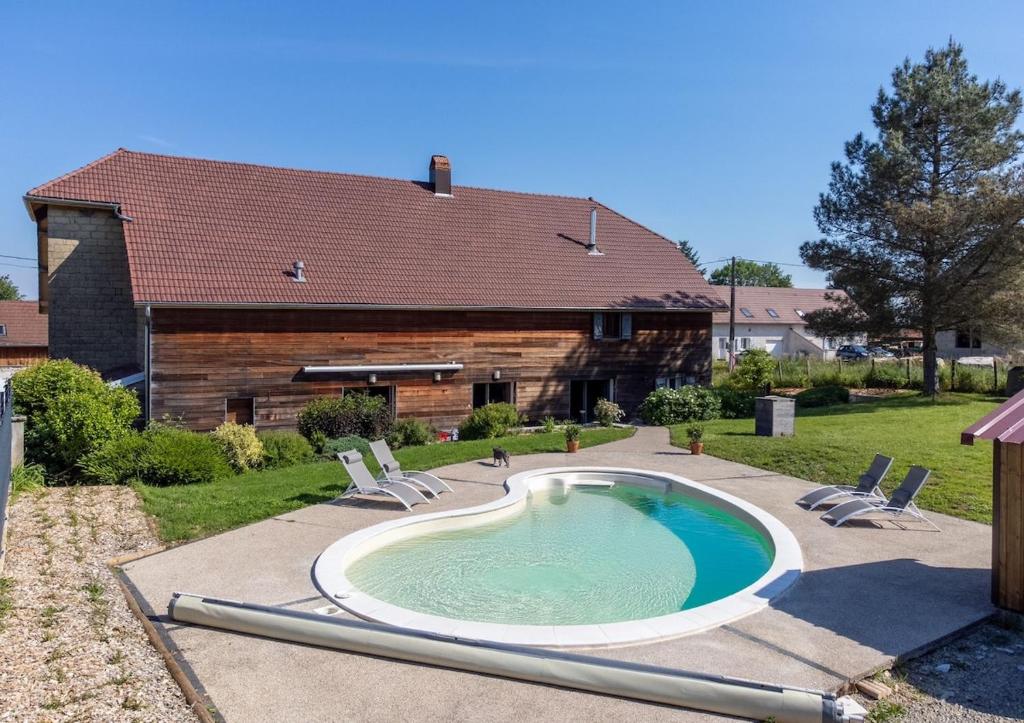 une piscine avec des chaises et une maison dans l'établissement Domaine Chez Feldus, à Villers-Farlay