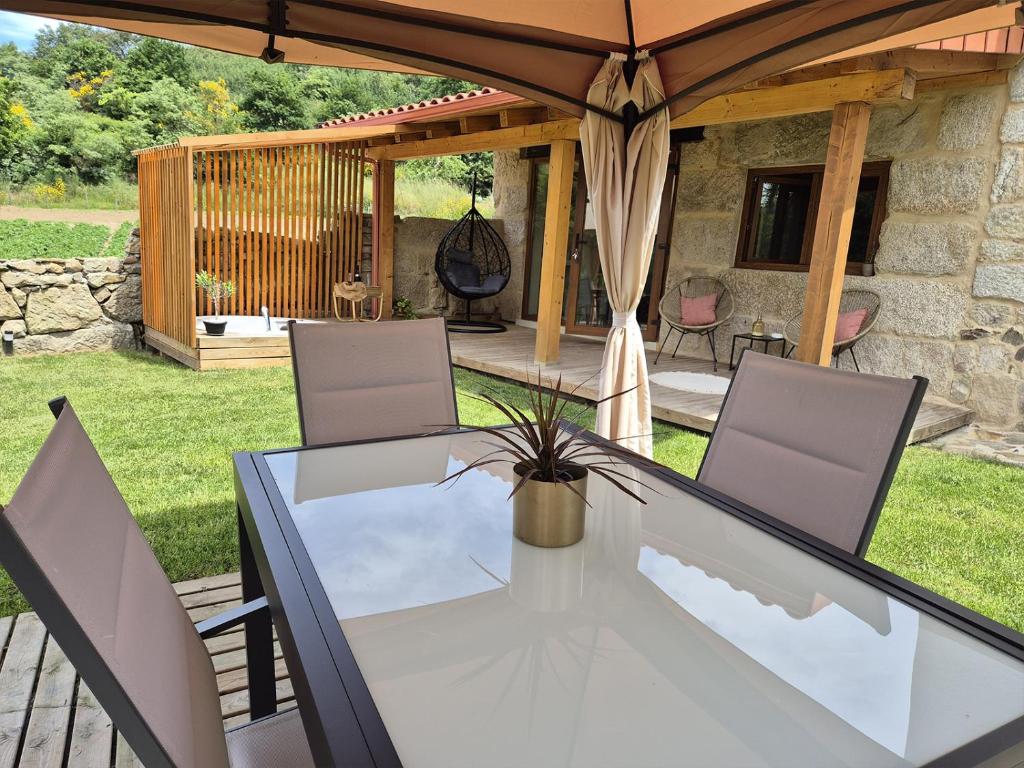 a dining table and chairs under an umbrella on a patio at Palleira da Aira in Entrambosríos