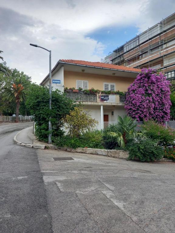 a building with a purple bush next to a street at Rooms Mirjana in Trogir